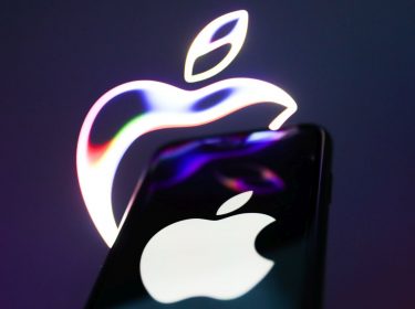 iPhone wird vor eine Leinwand mit Apple-Symbol gehalten