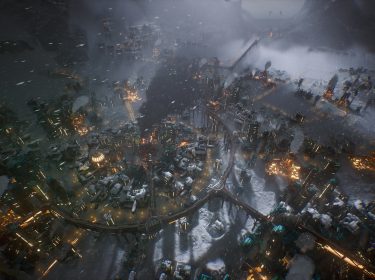 Auf dem Bild im Test zu Frostpunk 2 ist ein Screenshot vom Spiel zu sehen. Eine verschneite, post-apokalyptische Stadt bei Nacht, erhellt von vereinzelten Lichtern.