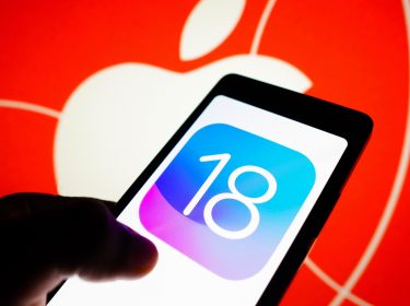 Hand hält Smartphone, auf dem Display die Zahl 18, im Hintergrund das Apple-Logo