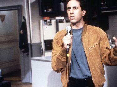 Jerry Seinfeld hält in den ersten Folgen der Seinfeld-Sitcom ein Mikrofon in der Hand