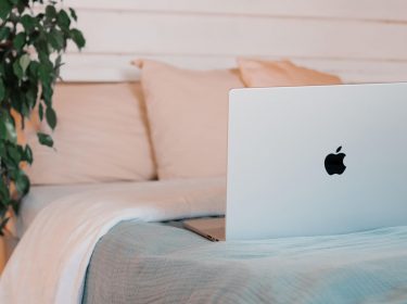 Apple MacBook liegt aufgeklappt auf einem Bett.