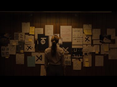 Eine Frau steht vor einer Pinnwand mit Zetteln über okkulte Hinweise