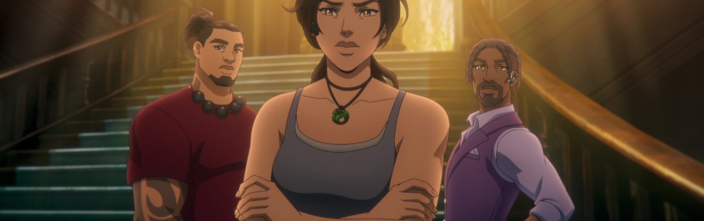 Auf dem Bild aus Tomb Raider: The Legend of Lara Croft stehen Lara Croft, Jonah Maiava und Allen Maldonado vor einer großen, eindrucksvollen Treppe in einem von Licht durchfluteten Gebäude. Lara, in einem grauen Tanktop und mit entschlossenem Blick, steht im Vordergrund mit verschränkten Armen. Hinter ihr sind Jonah, mit Tattoo und rotem Shirt, sowie Allen, in einem lila Anzug mit Ohrstück, zu sehen. Die Szene wirkt angespannt und dynamisch.