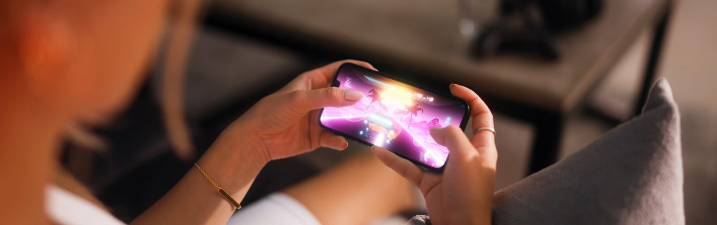 Eine Frau hält ein Handy in der Hand und spielt darauf ein Rennspiel.