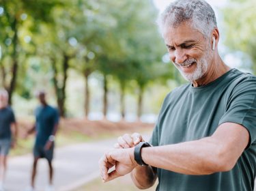 Ein älterer Herr schaut auf seine Smartwatch