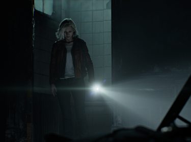 In dieser Szene aus Resident Evil Requiem betritt Protagonistin Grace Ashcroft einen düsteren, verfallenen Raum. Mit ernster Miene leuchtet sie mit einer Taschenlampe in die Dunkelheit. Die Umgebung wirkt verlassen und bedrohlich – schmutzige Kacheln, kaputte Möbel und schwaches Licht unterstreichen die unheimliche Atmosphäre von Resident Evil 9