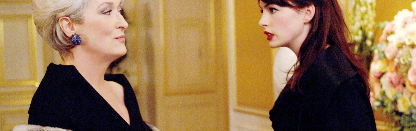 Auf dem Bild zum möglichen Film Der Teufel trägt Prada 2 sind Meryl Streep als Miranda Priestly und Anne Hathaway als Andy Sachs zu sehen. In einer eleganten Umgebung stehen sich die beiden Charaktere gegenüber. Miranda blickt kühl und überlegen, während Andy ernsthaft und entschlossen wirkt. Die Szene vermittelt Spannung und Stilbewusstsein.