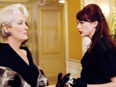 Auf dem Bild zum möglichen Film Der Teufel trägt Prada 2 sind Meryl Streep als Miranda Priestly und Anne Hathaway als Andy Sachs zu sehen. In einer eleganten Umgebung stehen sich die beiden Charaktere gegenüber. Miranda blickt kühl und überlegen, während Andy ernsthaft und entschlossen wirkt. Die Szene vermittelt Spannung und Stilbewusstsein.