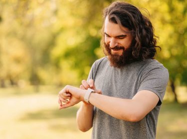 Junger Mann tipps draußen auf seine Smartwatch