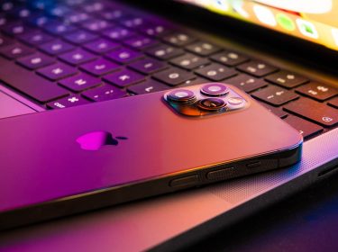 MacBook pro 2021 halb geöffnet, ein iPhone 13 liegt darauf