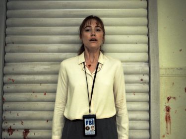 Eine Frau vor einer blutbespritzten Wand.