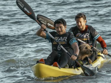 Auf diesem Bild zu den GigaTV Highlights im August sind die Schauspieler Mark Wahlberg (hinten) und Simu Liu (vorn) in einer actionreichen Szene im Film 