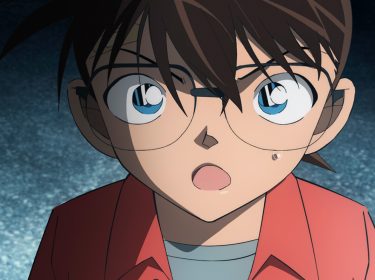 Im Bild im Artikel zum Kinofilm Detektiv Conan Film 27: Das 1-Million-Dollar-Pentagramm ist das Gesicht und die Schultern der Figur Detektiv Conan zu sehen. Der animierte Charakter schaut mit großen blauen Augen in die Kamera. Die dunkelbraunen Haare fallen ihm ins Gesicht. Seine Augenbrauen sind zusammengezogen, als wäre er wütend. Sein Mund ist geöfnet, als würde er gerade auf sein Gegenüber einreden. Dieses Gegenüber ist scheinbar viel größer als er, denn sein Kopf und sein Blick sind nach oben geneigt. Er trägt ein korallrotes Hemd und darunter ein graues T-Shirt.