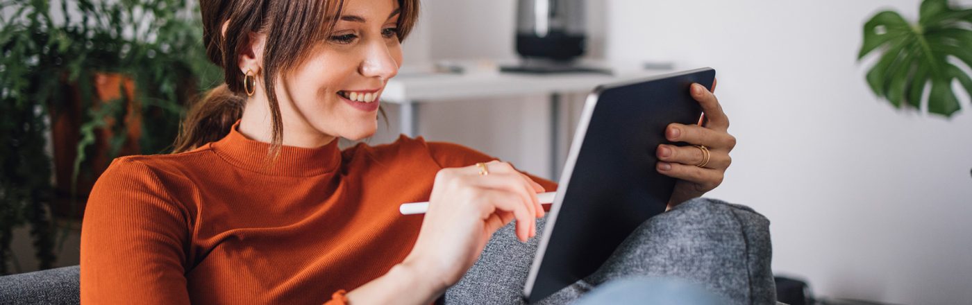 Auf dem Bild im Artikel dazu, wie Du Vodafone digital erreichen kannst, sitzt eine junge Frau entspannt auf einem Sofa und nutzt ein Tablet mit einem Eingabestift.