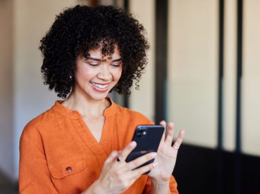 Frau lächelt und tippt auf ihr iPhone