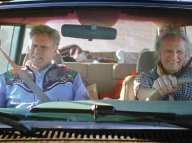 Auf dem Bild zu Will Ferrels-Netflix-Doku-Artikel fahren Will Ferrell und Harper Steele gemeinsam in einem Auto. Will Ferrell sitzt auf dem Beifahrersitz und trägt ein auffälliges Western-Hemd, während Harper Steele am Steuer lächelt. Beide wirken entspannt, die Rückbank ist mit verschiedenen Gegenständen gefüllt, was auf eine längere Fahrt oder Reise hindeutet.