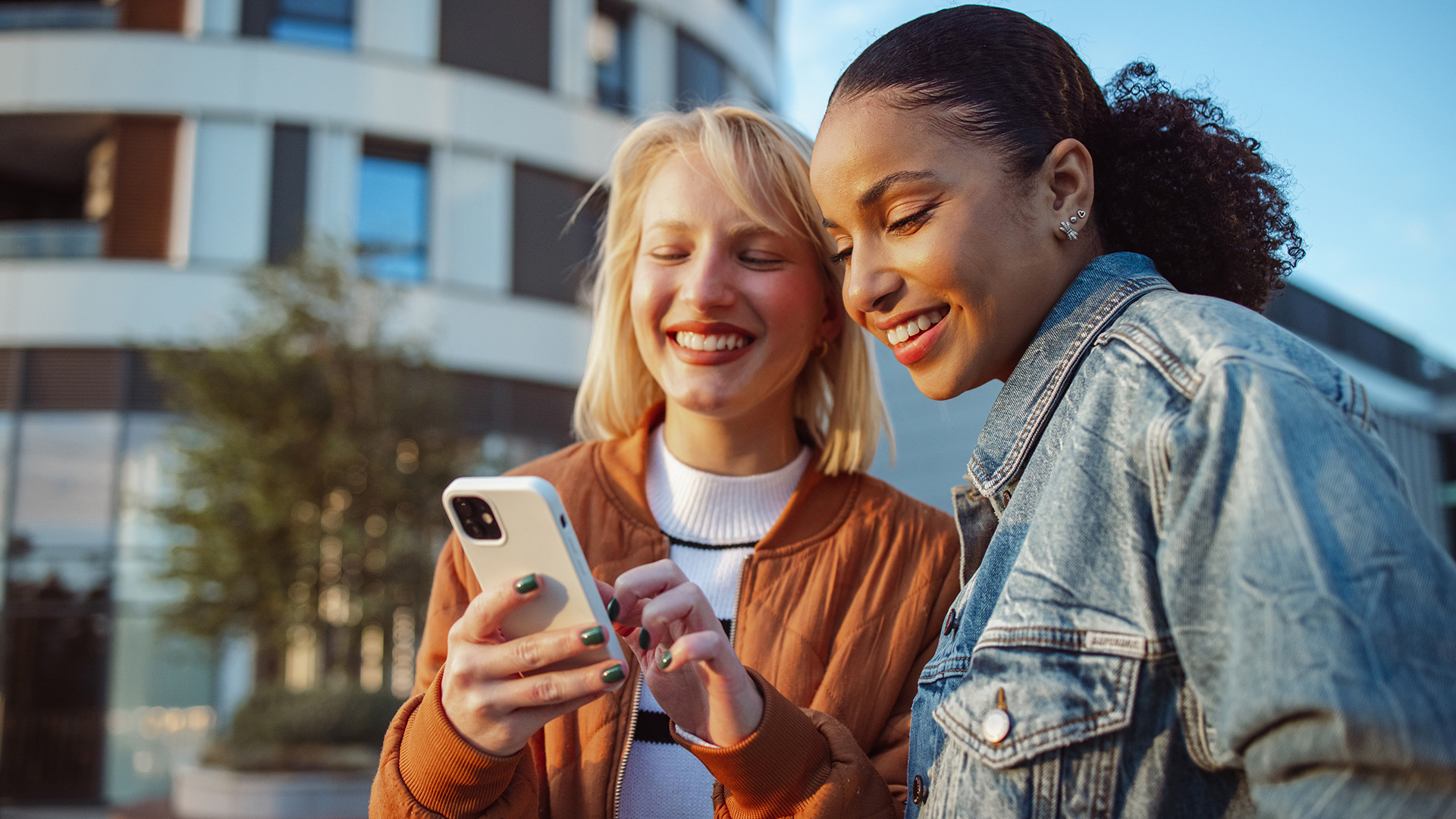 Auf dem Bild in dem Artikel zu Vodafone Young Tarifen lächeln zwei junge Frauen, während sie gemeinsam auf ein Smartphone schauen.