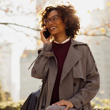 Auf dem Bild in dem Artikel zu den GigaMobil-Tarifen ist eine Frau mit Brille zu sehen, die lächelnd in einem herbstlichen Stadtpark telefoniert.