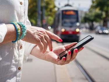 Frau mit lackierten Nägel tippt auf ihrem Smartphone