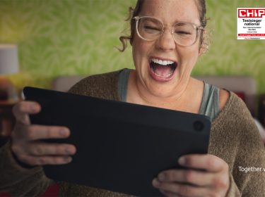 Im Bild des GoTestsieger-Artikels lacht eine Frau begeistert, während sie auf ein Tablet schaut. Im Hintergrund ist eine grüne, gemusterte Wand zu sehen. Oben rechts befinden sich zwei CHIP-Auszeichnungen, die Vodafone als führenden Internetanbieter in Deutschland kennzeichnen. Unten rechts ist der Vodafone-Slogan „Together we can“ zusammen mit dem Firmenlogo abgebildet.