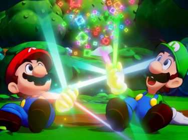 Auf dem Bild aus Mario & Luigi: Brothership Test sitzen die Brüder Mario und Luigi im Wald auf dem Boden und halten leuchtende, bunte Lichtstrahlen, die in der Luft schimmernde Quadrate erzeugen. Mario trägt seine typische rote Mütze und blaue Latzhose, während Luigi in grüner Mütze und blauer Latzhose strahlt. Beide wirken fröhlich und staunen über die magischen Effekte.