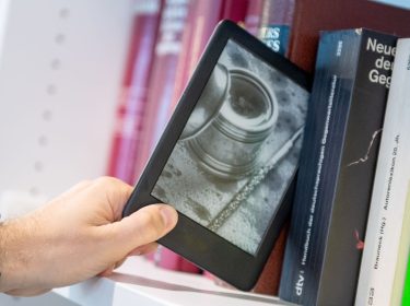 Ein Mann entnimmt ein E-Book-Reader Amazon Kindle in Berlin aus einem Buecherregal