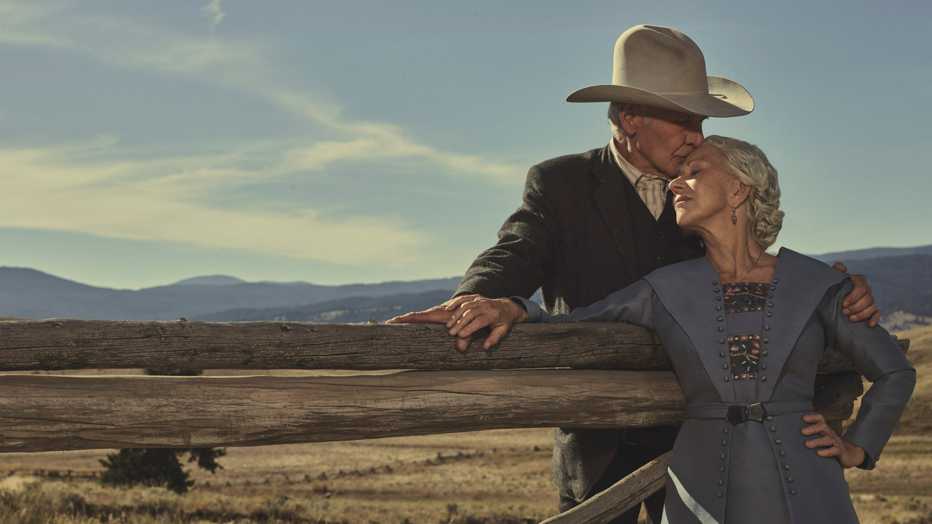 Auf dem Bild zur Yellowstone-Reihenfolge sind Jacob Dutton, gespielt von Harrison Ford, und Cara Dutton, dargestellt von Helen Mirren, in einer innigen Szene zu sehen. Vor der Kulisse der Weiten Montanas lehnt Jacob liebevoll an einem Holzzaun und küsst Cara zärtlich auf die Stirn. Die Szene strahlt Wärme, Vertrauen und tiefe Verbundenheit aus – typisch für die emotionale Tiefe der Yellowstone-Prequel-Serie 1923.