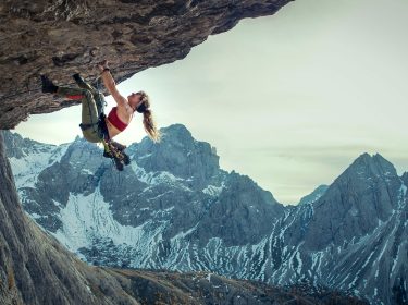 Auf dem Bild im Artikel über das Cliffhanger-Reboot ist zu sehen, wie die Schauspielerin Lily James an einem Berg klettert. Im Hintergrund sind weitere Berge zu sehen.