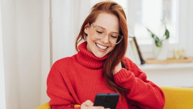 Auf dem Bild in dem Artikel zur Rufnummermitnahme bei Vodafone ist eine Frau mit Brille und einem Handy zu sehen.