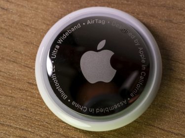 Der runde Apple AirTag liegt auf einem Holztisch.