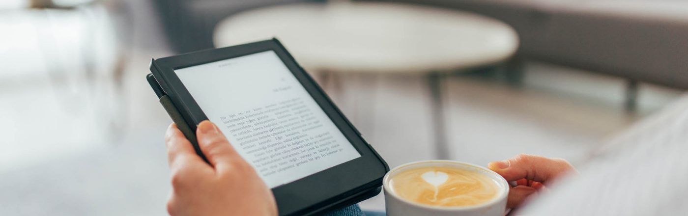 Ein E-Book-Reader in den Händler einer Frau, die auf der Couch liest