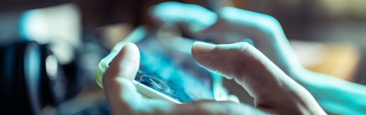 Das Bild in dem Artikel über die besten Koop-Games fürs Handy, zeigt eine Nahaufnahme von Händen, die ein Smartphone im Querformat halten. Der Fokus liegt auf den Fingern und dem Bildschirm, der unscharf, aber lebendig wirkt. Die Atmosphäre ist konzentriert, das Spielgeschehen spiegelt sich leicht auf dem Display wider.