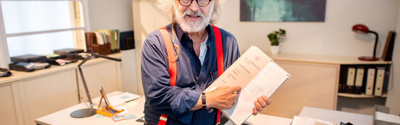 Klaus-Peter Wolf sitzt auf dem Schreibtisch der Hauptkommissarin Ann Kathrin Klaasen aus den Ostfriesenkrimis