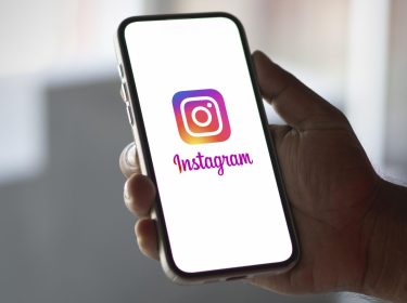 Das Logo von Instagram ist auf einem Smartphone abgebildet, das jemand in der Hand hält.