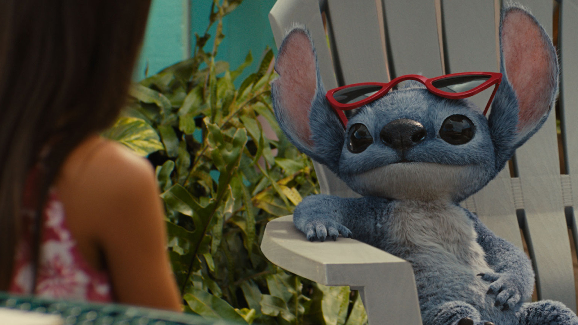 In der Szene aus den Disney Realverfilmungen 2026 sieht man Catherine Laga'aia als Vaiana auf einem traditionellen Segelboot bei Sonnenuntergang. Sie trägt ein rotes, gemustertes Oberteil und eine grüne Muschelkette. Mit offenem Mund und freudigem Blick hält sie sich an einem Seil fest, während das Segel im Hintergrund sichtbar ist. Die Stimmung wirkt abenteuerlich und optimistisch.