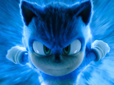 Auf dem Bild aus dem Film Sonic the Hedgehog 3 ist Sonic, die ikonische blaue Figur, in einer dynamischen Nahaufnahme zu sehen. Sein entschlossener Blick richtet sich direkt auf den Betrachter, während er mit scheinbar hoher Geschwindigkeit durch eine blaue Energiewelle rast. Das Bild ist in dem Artikel über Sonic 4 zu sehen.