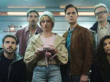 Die Crew von Berlin steht versammelt vor einem Gemälde.