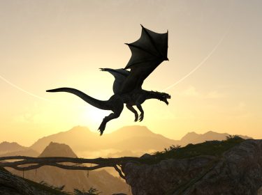 Vor einer goldenen Abendsonne fliegt ein majestätischer Drache mit ausgebreiteten Flügeln über eine felsige Landschaft. Im Hintergrund sind Berge und ein leicht nebliger Himmel zu sehen. Dieses Symbolbild steht für die Fantasiewelt der 