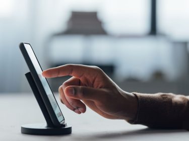 Mann tippt mit seinem Finger auf das Display eines Smartphones