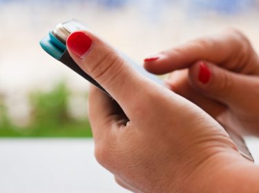 Frau tippt auf das Display ihres Smartphones.