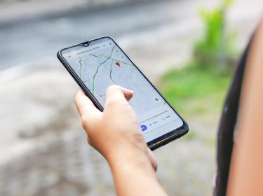 Eine Person hält ein Smartphone mit geöffneter Google-Maps-App in der Hand