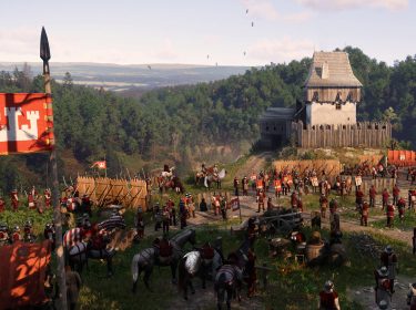 Auf dem Bild in dem Artikel zum Kingdom Come: Deliverance 2 Test ist ein mittelalterliches Militärlager vor einer hölzernen Festung zu sehen. Zahlreiche Soldaten in roten Wappenröcken und Metallhelmen stehen in Formation. Fahnen mit einem Wappen aus weißen Türmen auf rotem Grund wehen im Wind. Im Hintergrund erstreckt sich eine grüne Hügellandschaft unter einem klaren Himmel. Die Szene wirkt lebendig und strategisch angespannt.