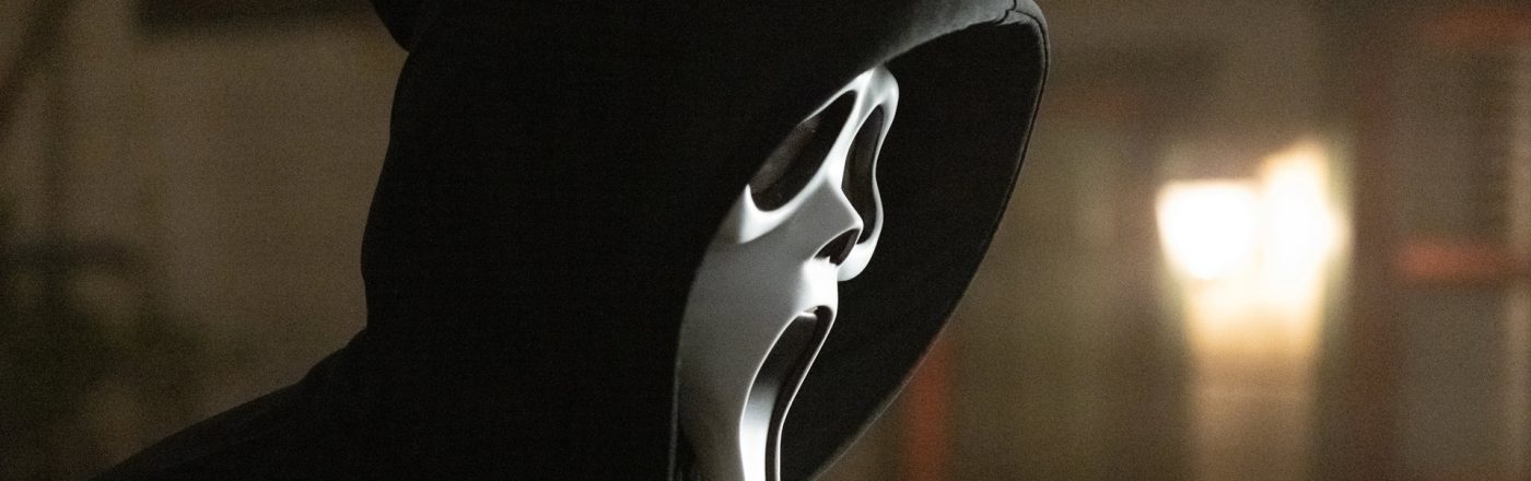 Auf dem Bild zu Scream 7 ist der ikonische Killer Ghost Face zu sehen. Er trägt eine schwarze Kapuze und die bekannte weiße Maske mit weit aufgerissenem Mund und leeren Augen. Die Szene wirkt düster und unheimlich, mit verschwommenen Lichtern im Hintergrund, die eine bedrohliche Atmosphäre erzeugen