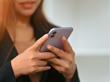 Junge Frau hält ein iPhone in ihren Händen