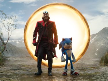 Auf dem Bild zu den GigaTV Highlights im März sind Jim Carrey als Dr. Ivo Robotnik, auch bekannt als Dr. Eggman, und Sonic zu sehen. Sie stehen vor einem leuchtenden, goldenen Portal in einer bergigen Landschaft. Dr. Robotnik trägt einen schwarzen Mantel mit roten Akzenten und eine Schutzbrille auf der Stirn, während Sonic mit verschränkten Armen entschlossen wirkt. Die Szene vermittelt Spannung und Abenteuer.