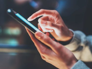 Die Hand einer Frau tippt auf ein Smartphone-Display