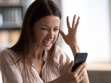 Eine Frau schaut verärgert auf ihr Smartphone.