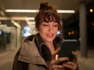 Eine junge Frau hält ein Smartphone in den Händen.