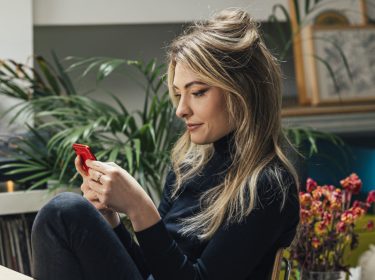 Eine junge Frau schaut auf ihre Smartphone.
