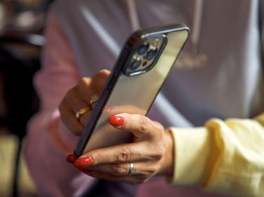 Frau zeigt mit ihrer Hand auf etwas auf dem iPhone.